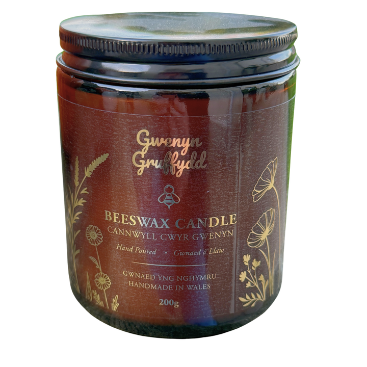 Gwenyn Gruffydd 200g pure British beeswax candle in an amber glass jar with gold lettering, handmade in West Wales.