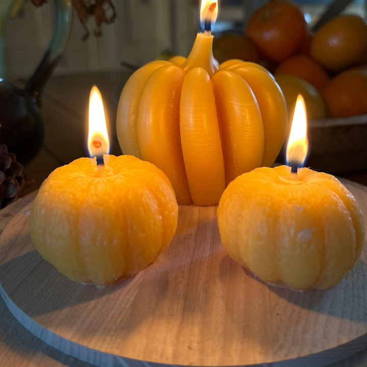 Lit mini beeswax pumpkin candles with large pumpkin candle for autumn décor
